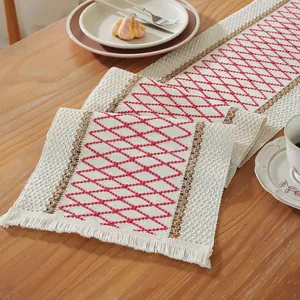 Detail of red geometric diamond embroidery and white tassels on a woven cotton table runner