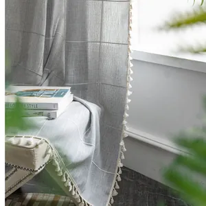 Detail of grey linen-textured curtain with white plaid pattern and creamy tassels