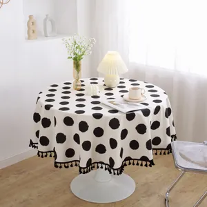 Mantel redondo blanco minimalista con lunares negros y borlas decorativas