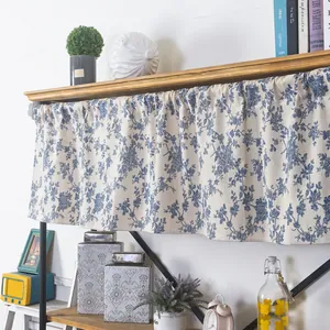 Detail of blue olive leaf print on linen cafe curtain with pleated header on wooden shelf