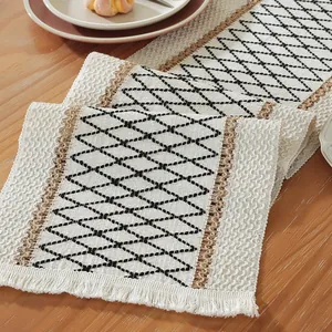 Detail of cotton linen table runner with geometric weave patterns and tassel trim