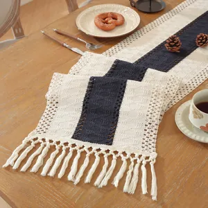 Detail van gebreid patroon op de marineblauwe en beige tafelloper met witte kwastjes