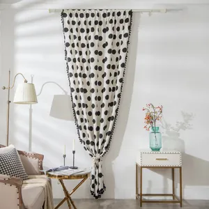 Detalle de cortina de algodón crema con lunares negros y elegante borde de flecos