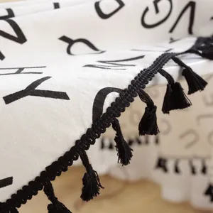 Primer plano de mantel de algodón y lino con borlas negras y diseño de letras nórdicas