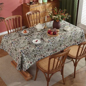 Detail view of jacquard floral tablecloth with dense plant patterns on wooden table