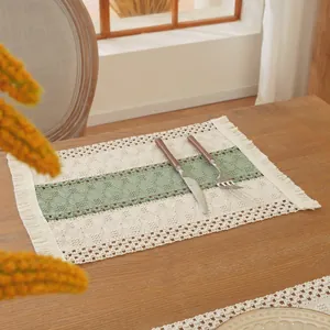 Detalle de mantel individual nórdico tejido con motivos verdes, flecos y cubiertos