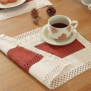 Detalle de mantel individual tejido en algodón con flecos en beige y rojo ladrillo