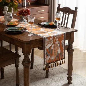 Détail d'un chemin de table jacquard rétro orange avec glands et motifs floraux de feuilles