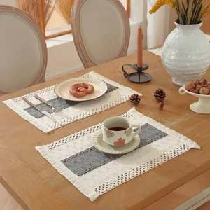Primer plano de un mantel individual tejido con borlas sobre mesa de madera para cena acogedora