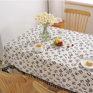 Detail der Leinen-Tischdecke mit schwarzem Buchstabendruck und eleganten Fransen