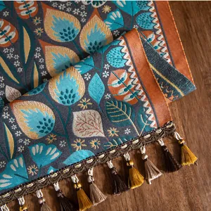 Détail de chemin de table en jacquard vintage avec motifs floraux et pompons colorés