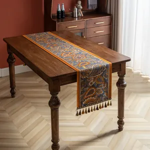 Détail d'un chemin de table jacquard à motif cachemire et franges sur table en bois