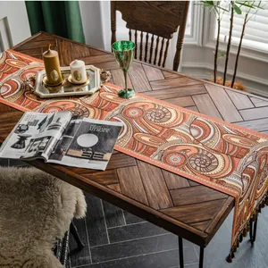 Détail du chemin de table jacquard rétro orange avec des glands décoratifs marron chic