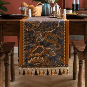 Détail d'un chemin de table jacquard à motif paisley avec pompons dégradés