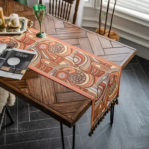 Gros plan d'un chemin de table jacquard géométrique avec glands sur table en bois