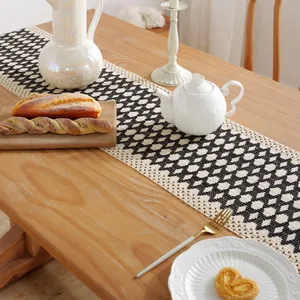 Nordic black and white geometric diamond crochet table runner with tassels on a dining table