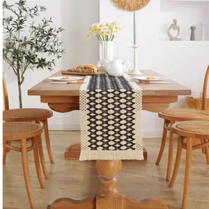 Modern minimalist black and white geometric woven table runner with tassels on a wooden table