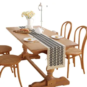 Nordic black and white geometric table runner with tassels on a rustic wooden table
