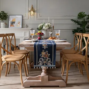 Détail du chemin de table en jacquard avec broderies florales et pompons en perles bleues