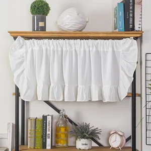 Detail of white ruffle-edged kitchen cafe curtain in a cozy home interior setting