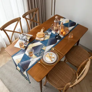 Vue détaillée du chemin de table jacquard avec motifs géométriques et pompons verts