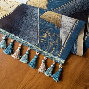 Détail d'un chemin de table en jacquard aux motifs géométriques et pompons bicolores
