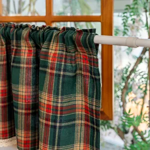 Detail of red and green plaid short curtain with white lace trim on a white rod