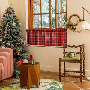 Detail of red plaid cafe curtain with white lace edging in a cozy Christmas setting