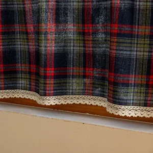 Close-up of tartan pattern fabric with cream lace trim on a wooden window sill