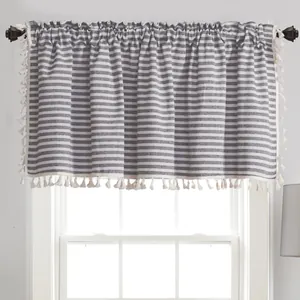 Détail d'un rideau court rayé gris et blanc avec une bordure décorative à pompons blancs