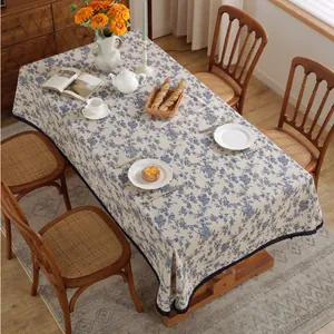 Détail de la nappe en lin de style champêtre avec imprimés floraux bleus et bordure dentelle