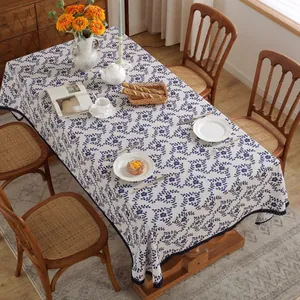 Detail van blauw gebloemd tafelkleed met decoratieve kantranden op een houten tafel