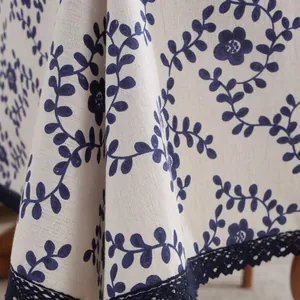 Detail van de marineblauwe bloemenprint en kanten rand op een beige katoenen tafelkleed