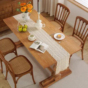 Close-up of cream crochet table runner with intricate lace hollow-out patterns and long tassels