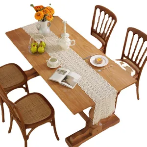 Elegant cream lace table runner with intricate hollow-out patterns and tassel edges