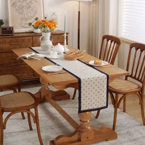 Gros plan sur la bordure en dentelle bleue et le motif floral du chemin de table en lin