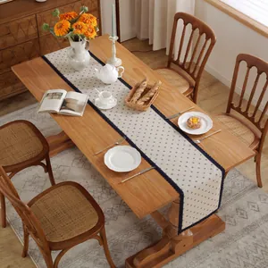 Détail du chemin de table crème avec motifs floraux bleus et bordure en dentelle