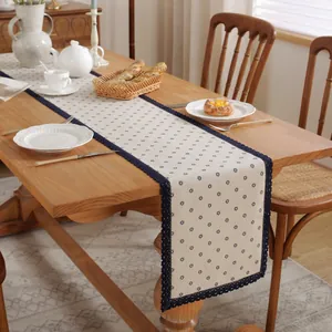 Détail d'un chemin de table crème avec imprimé floral bleu et bordure en dentelle chic