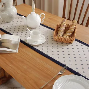 Détail de fleurs bleues et dentelle bleu marine sur un chemin de table en lin