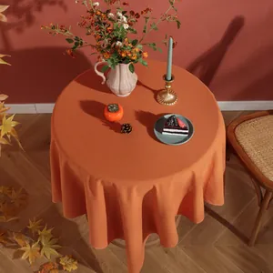 Detail of round orange linen tablecloth with natural drape for festive home decoration