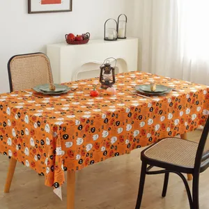 Detail of orange Halloween tablecloth featuring ghosts, pumpkins, and spiders on linen fabric