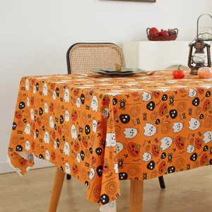 Halloween festive tablecloth detail featuring orange pumpkins and ghosts in a cozy home setting