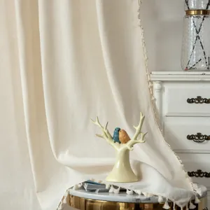 Detail of linen stripe curtain with decorative pom-pom fringe in a cozy home setting