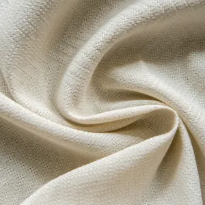 Macro view of cream cotton linen fabric with distinct chevron weave texture and soft finish