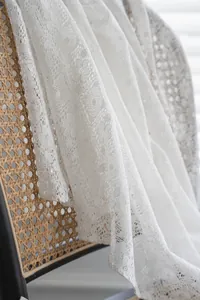 Detailed close-up of white floral lace fabric with intricate clover hollow pattern