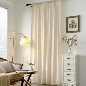 Close-up of beige linen curtain showing bohemian tassels and rod pocket construction