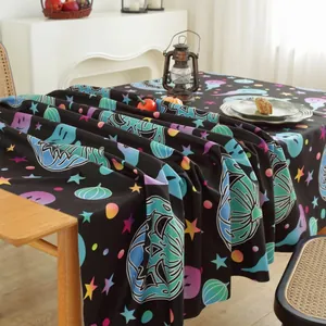 Close-up of Halloween tablecloth featuring colorful pumpkins and ghosts on black linen fabric