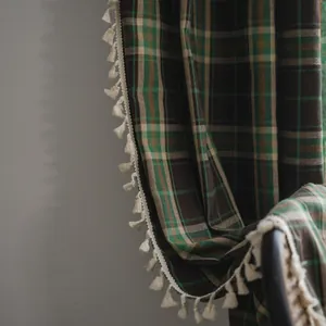 Close-up of vintage red and green plaid curtain fabric with decorative white cotton tassels