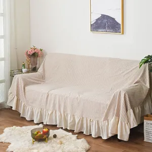 Close-up of beige striped sofa cover featuring elegant ruffled edges and linen texture