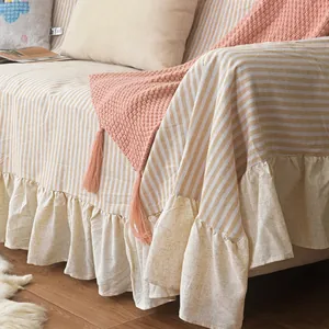 Detail of yellow and white striped sofa cover with elegant cream ruffle edges